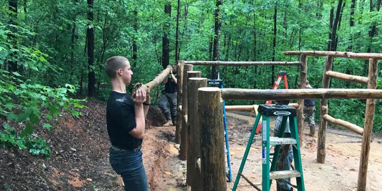 Samuel helping to build a tent at camp